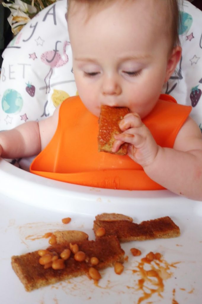 My daughter, Cara, eating beans on toast as part of baby led weaning.