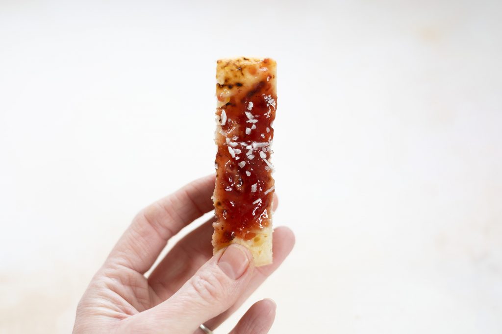 Fruit spread and shredded coconut on a crumpet finger.