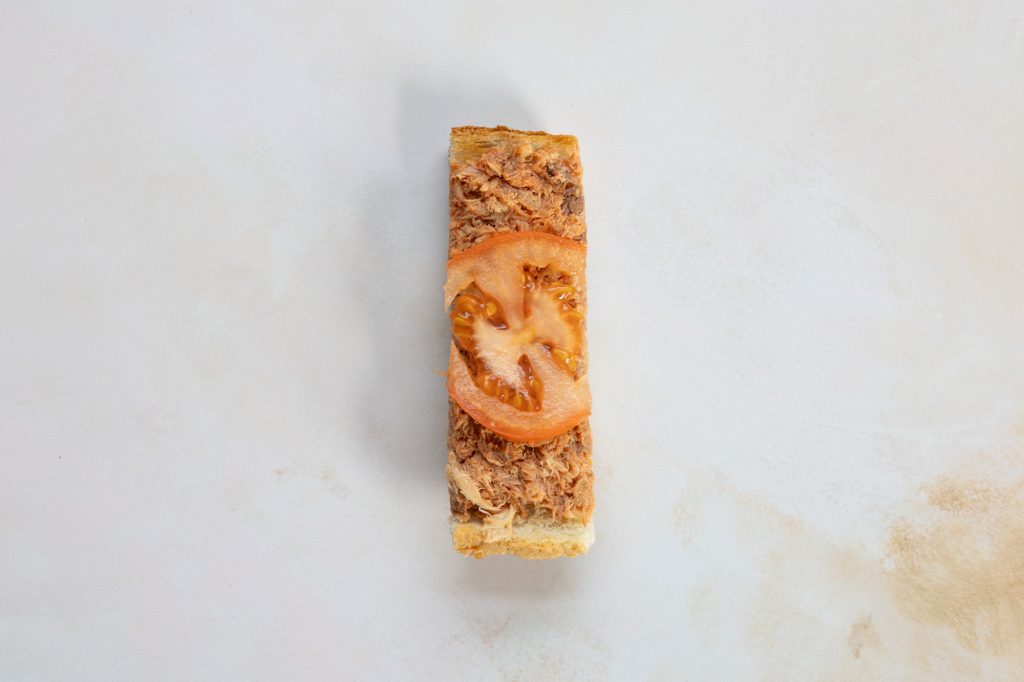 Tinned mackerel on toast with tomato puree and a thin tomato slice.