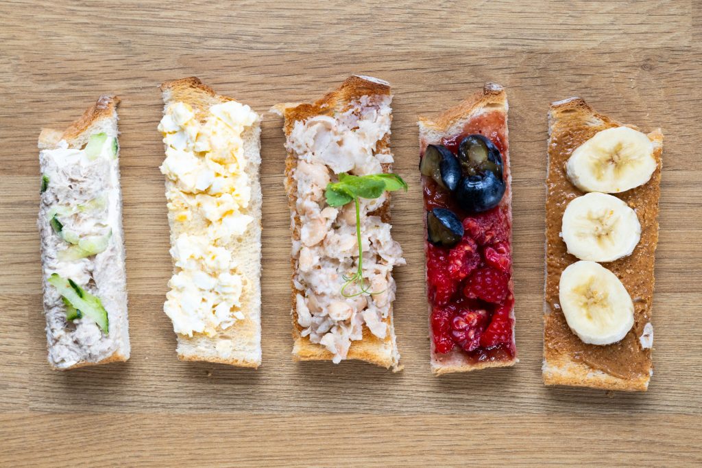 Five different toast fingers showing toppings: tuna, egg, haricot bean, mashed berries, and peanut butter and egg.